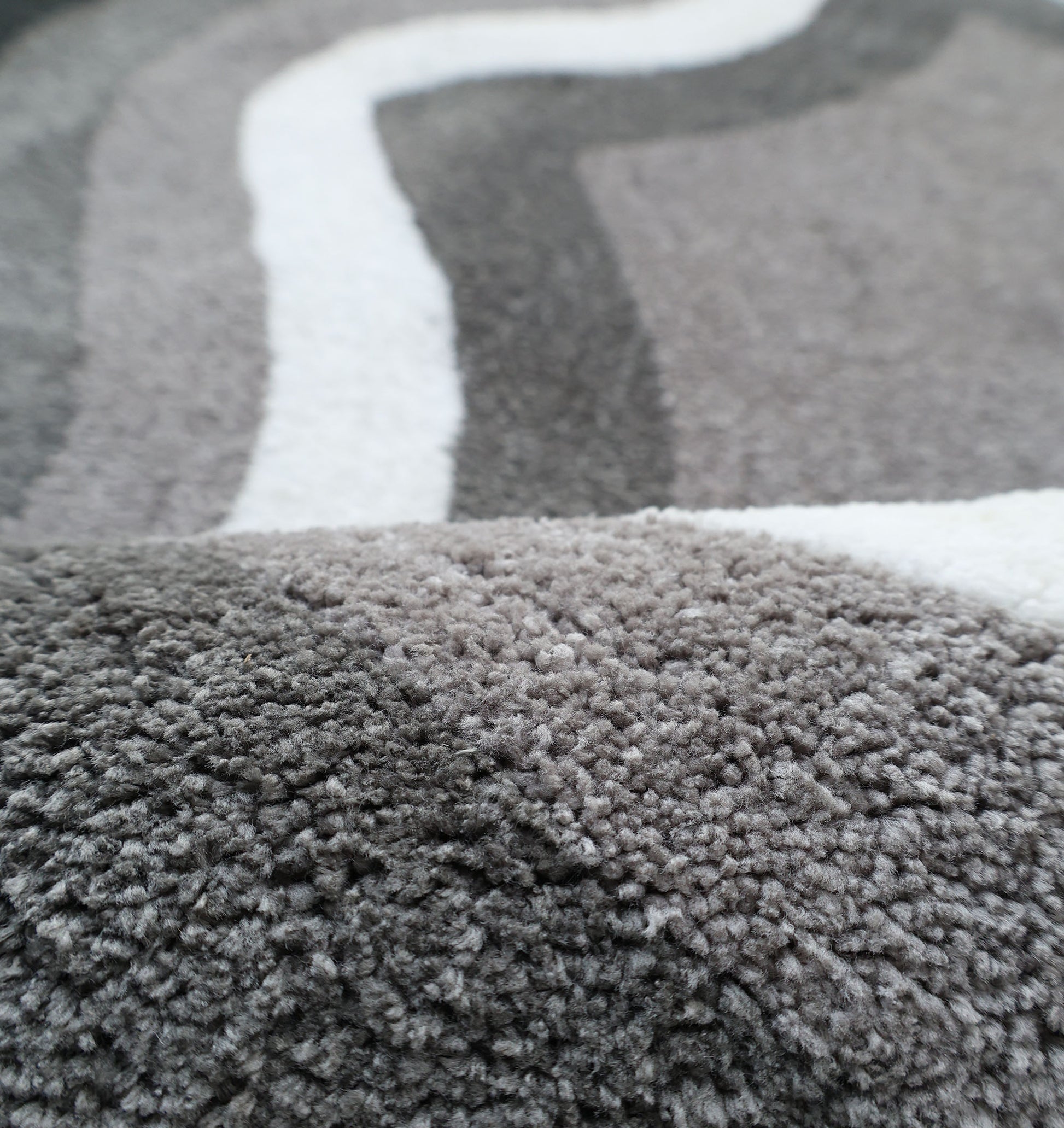 The RAMSHA HOME Modern Border Layered Irregular Soft Shaggy Carpet - SG 054 features a cozy, fluffy 3D texture with wavy grey and white stripes, adding warmth and inviting style to any space.