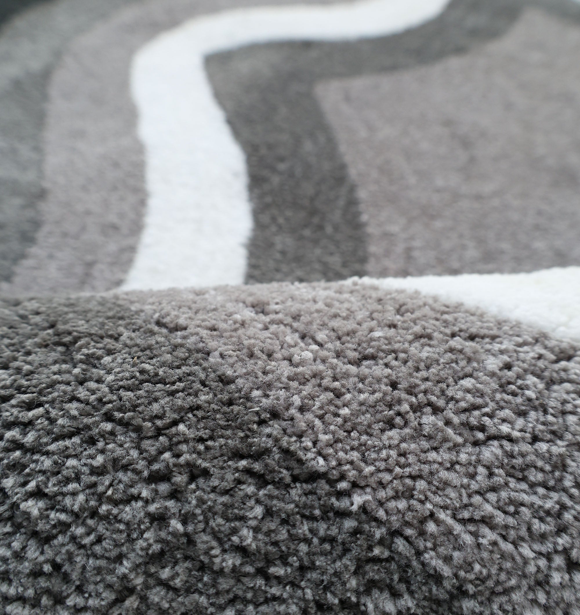 The RAMSHA HOME Modern Border Layered Irregular Soft Shaggy Carpet - SG 054 features a cozy, fluffy 3D texture with wavy grey and white stripes, adding warmth and inviting style to any space.