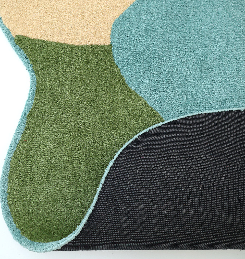 The RAMSHA HOME Modern Multicolor Irregular Soft Shaggy Carpet - SG 056 features organic shapes in green, beige, and teal with a textured black backing, showcasing its thickness—ideal for adding cozy, modern style to any space.