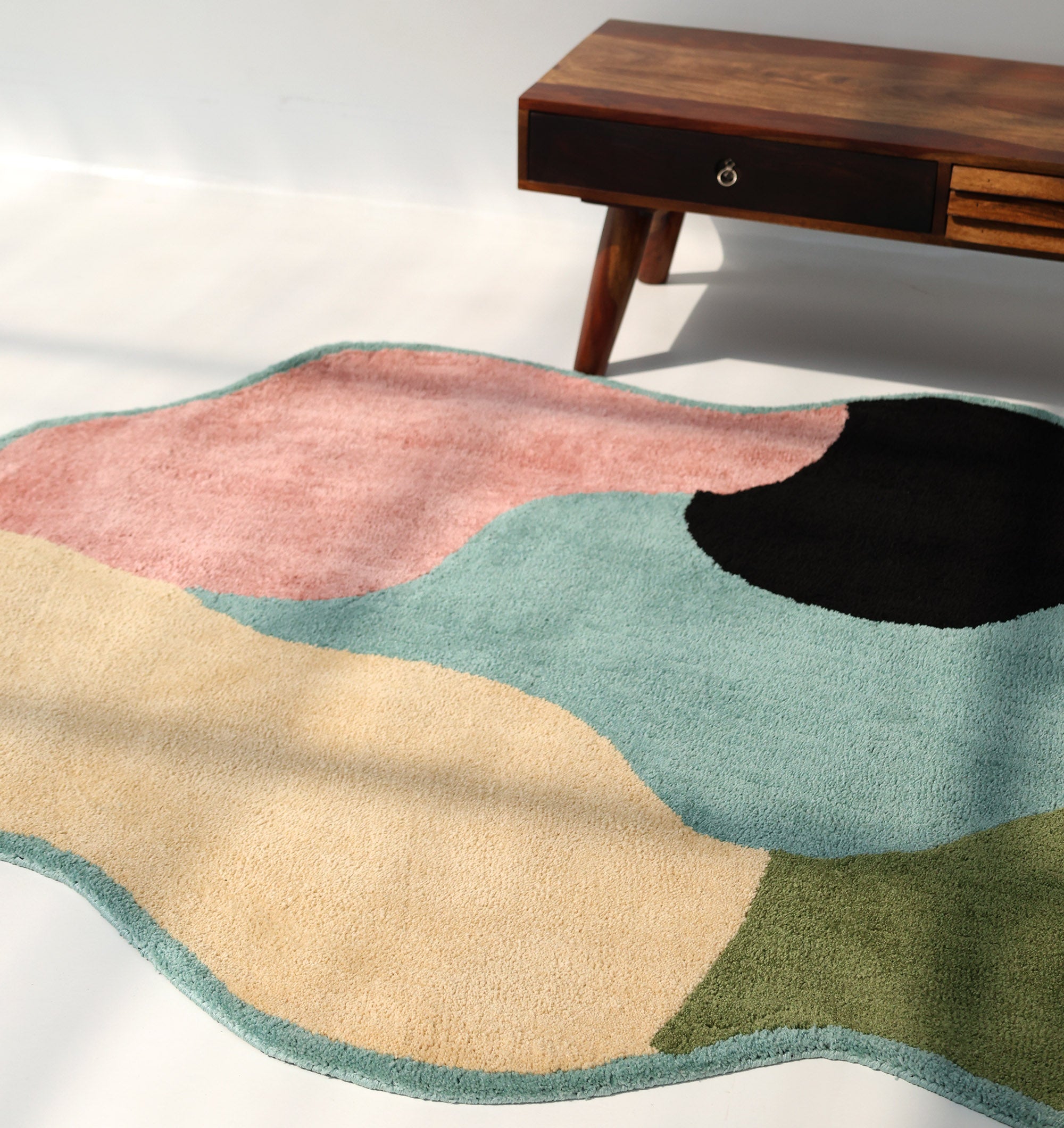 The RAMSHA HOME Modern Multicolor Irregular Soft Shaggy Carpet (SG 056) features pastel pink, cream, green, teal, and black accents—an ideal addition to cozy home décor and perfect beside a mid-century table.