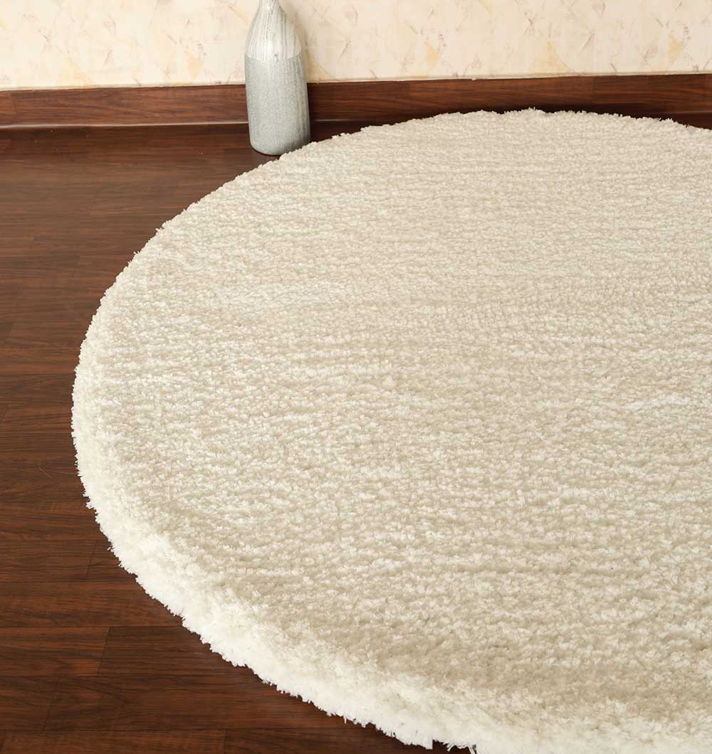 The RAMSHA HOME Round Soft White Shaggy Rug - SG 06 rests on a polished dark wood floor, with a light-colored vase placed near the wall in the background.