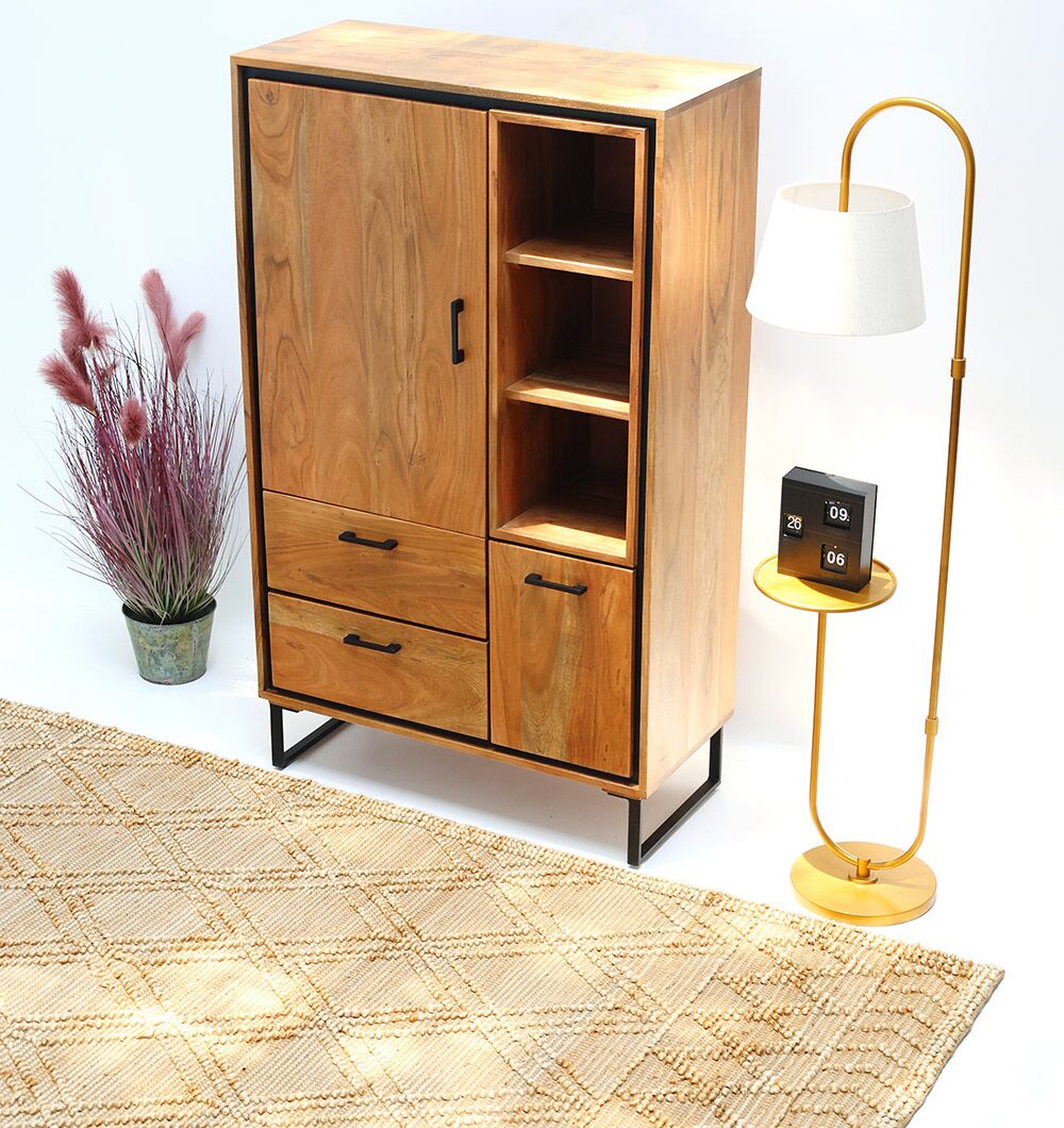The Handcrafted Acacia Wood Cabinet Almirah with open shelves by RAMSHA HOME stands in the living room beside a modern gold floor lamp with a white shade, a flip clock, a potted plant, and a patterned beige rug on the white floor.