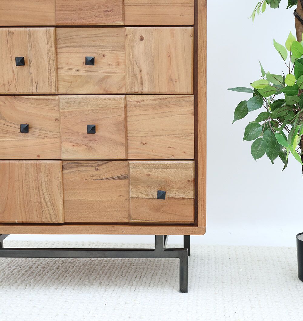 The RAMSHA HOME Natural Acacia Wood Drawer Cabinet – 8 Drawer Cabinet features square, textured drawer fronts with black knobs and sleek black metal legs, shown beside a leafy green potted plant on a light-colored carpet.