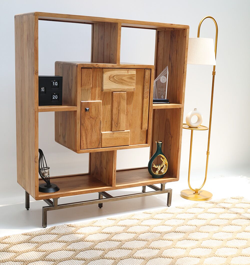 The RAMSHA HOME Wooden Book Shelf With Central Cabinet features open compartments and a central cabinet in acacia wood on a metal base, displaying decor pieces beside a modern gold floor lamp atop a woven rug.