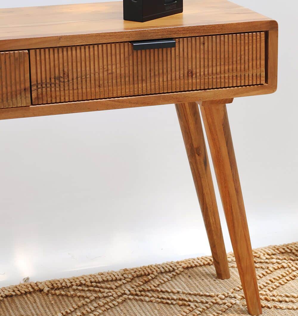 A close-up of the RAMSHA HOME Wooden Sideboard Cabinet with Storage in solid acacia, featuring grooved drawer fronts and angled legs, displayed on a textured beige rug with a geometric pattern.