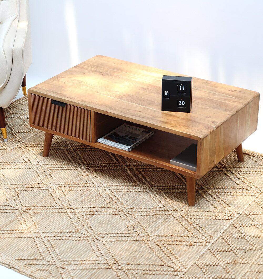 The RAMSHA HOME Modern Industrial Acacia Wood Sideboard with Black Metal Base sits on a beige patterned rug next to a white armchair, designed to complement any modern TV unit and topped with a small digital calendar clock.