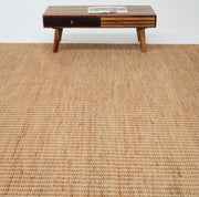 The RAMSHA HOME Handmade Natural Color Hand Woven Area Rug SR-062 lies on the floor, paired with a mid-century modern wooden coffee table holding a magazine, all set against a plain white background.