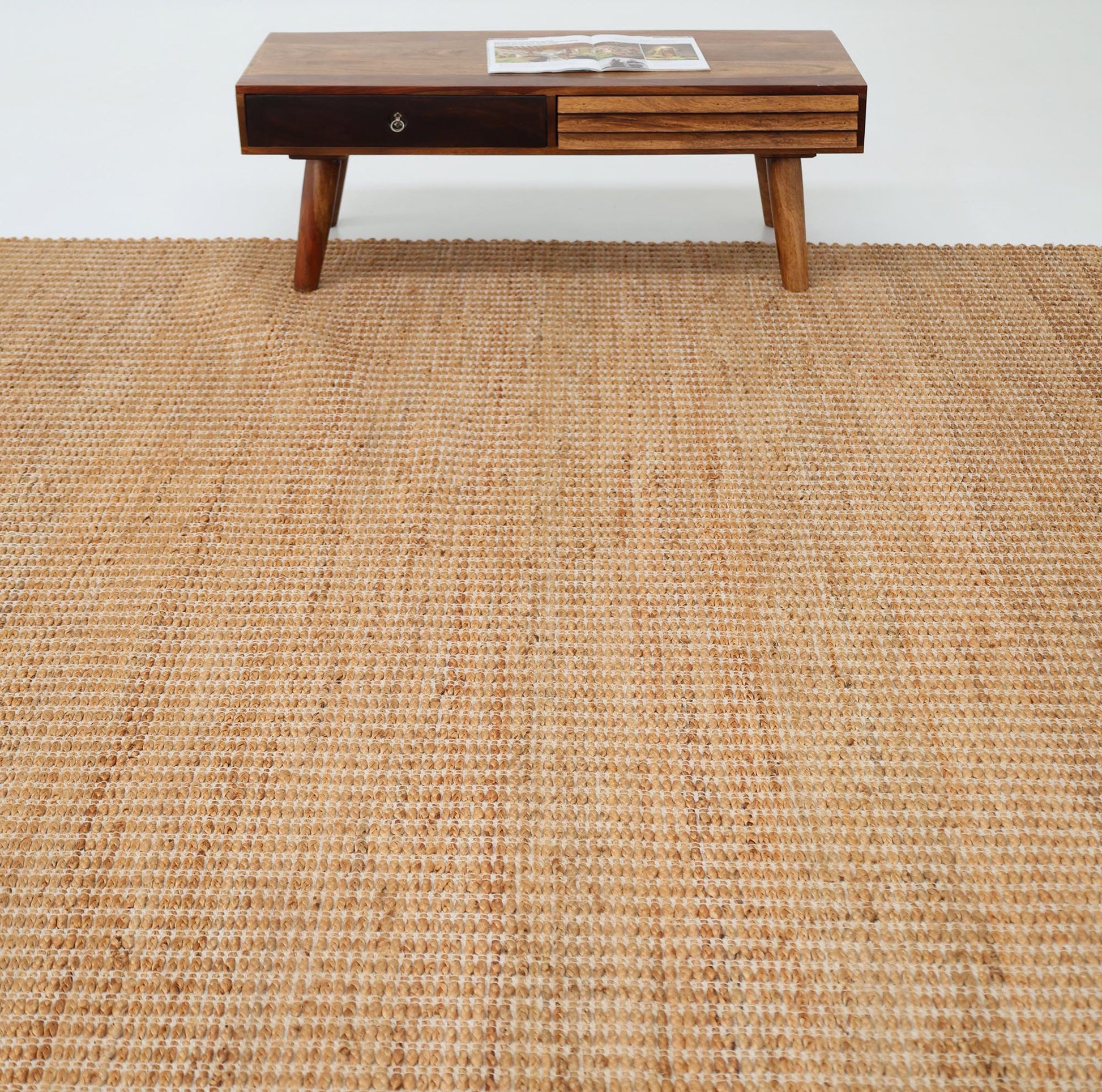 The RAMSHA HOME Handmade Natural Color Hand Woven Area Rug SR-062 lies on the floor, paired with a mid-century modern wooden coffee table holding a magazine, all set against a plain white background.