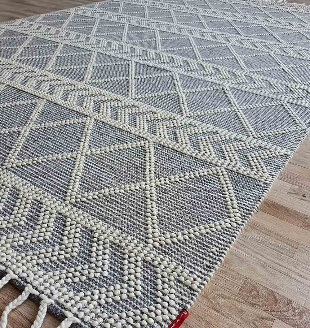 The RAMSHA HOME Ramadan Prayer Rugs Natural White Floor Woven Rug (SRN 020) features a geometric diamond and zigzag pattern in white/light gray, textured raised designs, and fringes on one edge, displayed on a light wooden floor.