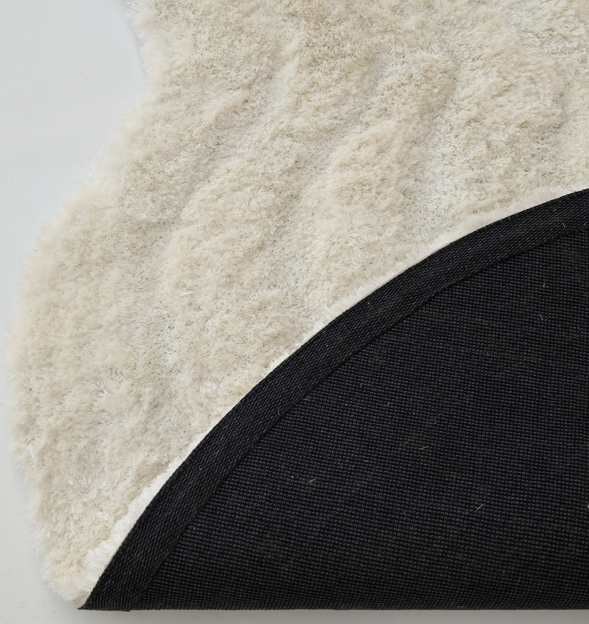 A close-up highlights the white, fluffy texture of the RAMSHA HOME White Irregular Shaped Home Decor Shaggy Rug - SG 040 3D, with one corner flipped over to display its black woven underside.