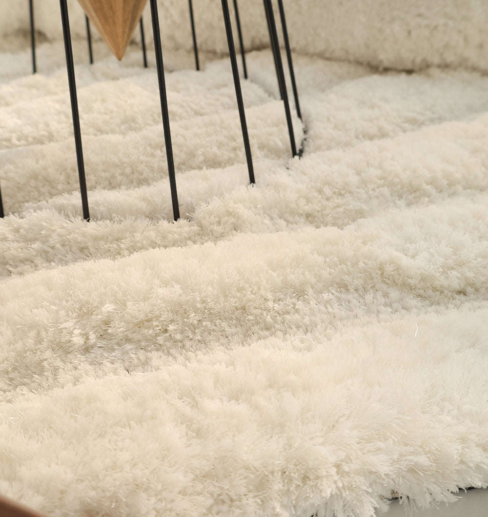 Close-up of the White irregular Shaped Home Decor Shaggy Rug - SG 040 3D by RAMSHA HOME, showcasing its soft, fluffy texture. Black metal legs of a furniture piece are visible in the background, highlighting the modern design of this unique living room rug.
