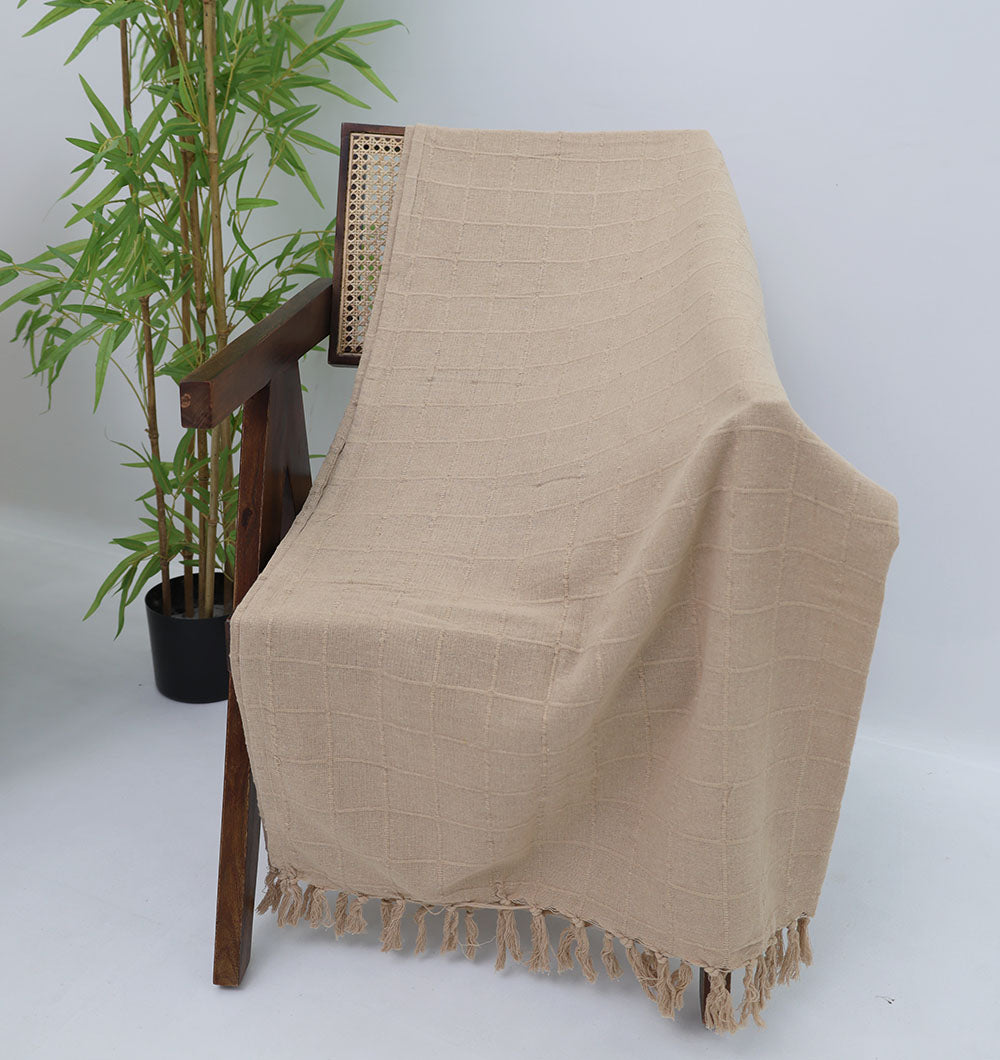 The Living Room Throw Beige Color TAL 052 (130x160cm) by Ramsha Home, draped over a woven-back wooden chair, adds modern comfort and style to this bright minimalist room with a potted bamboo plant nearby.