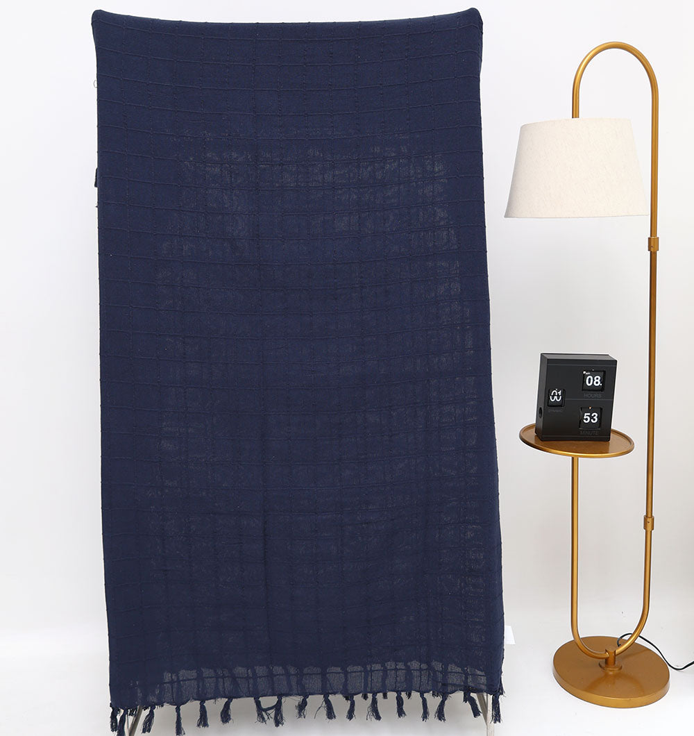 The Ramsha Home Living Room Throw Navy Blue Color TAL 055 (130x160cm) hangs beside a modern gold floor lamp and a side table with a digital clock, set against a plain white background—ideal for adding luxury to your sofa.