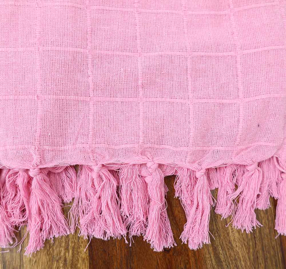 The Living Room Throw Pink Color TAL 056 (130x160cm) by Ramsha Home features a subtle check pattern and twisted fringe tassels, adding elegance to any living room decor. Perfect for draping on wooden surfaces.