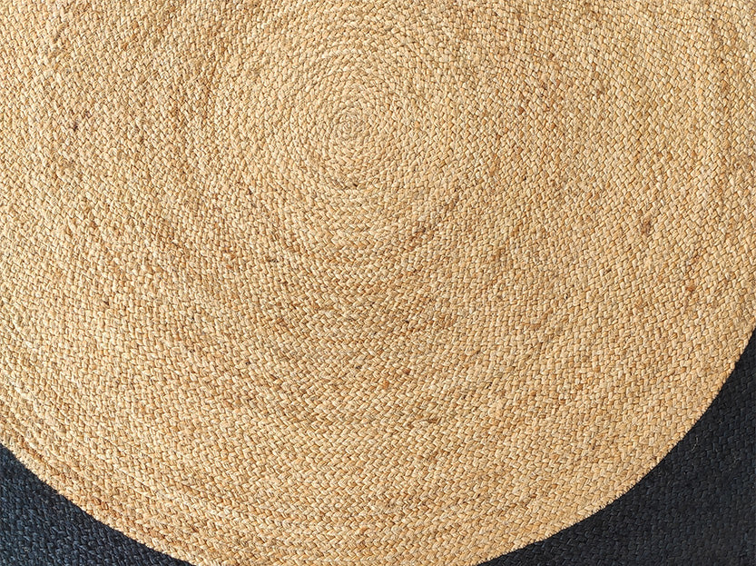 Close-up of the RAMSHA HOME Beautiful Handmade Braided Jute Floor Round Rug - BR 057 (200cm) showing its natural tan spiral pattern and partially visible black border.