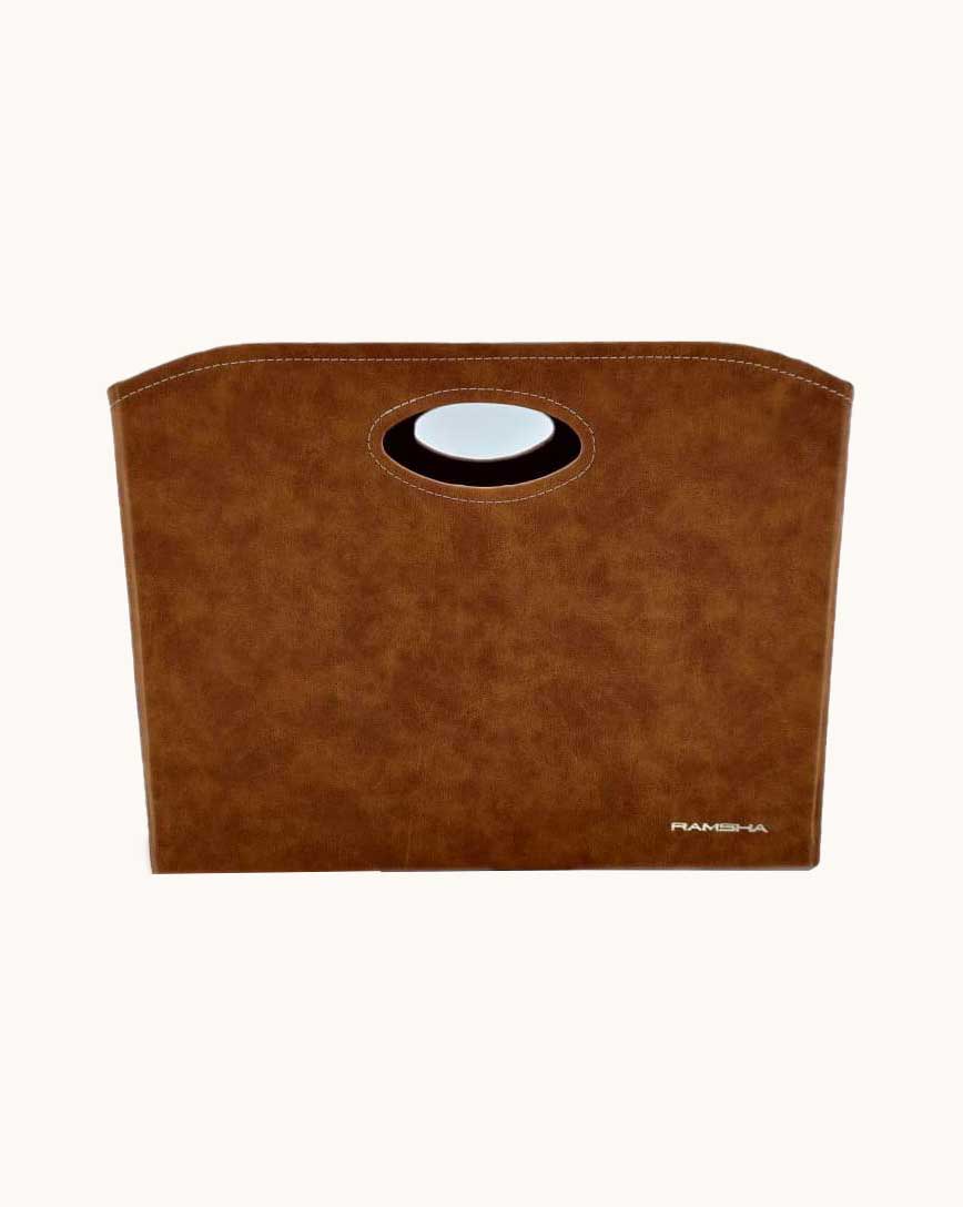 The Tan Handmade Polyester Basket - BK 001 (35x20x27cm) by Ramsha Home features a rounded oval cutout handle and a subtle logo, offering versatile storage for essentials. Photographed against a plain light background.