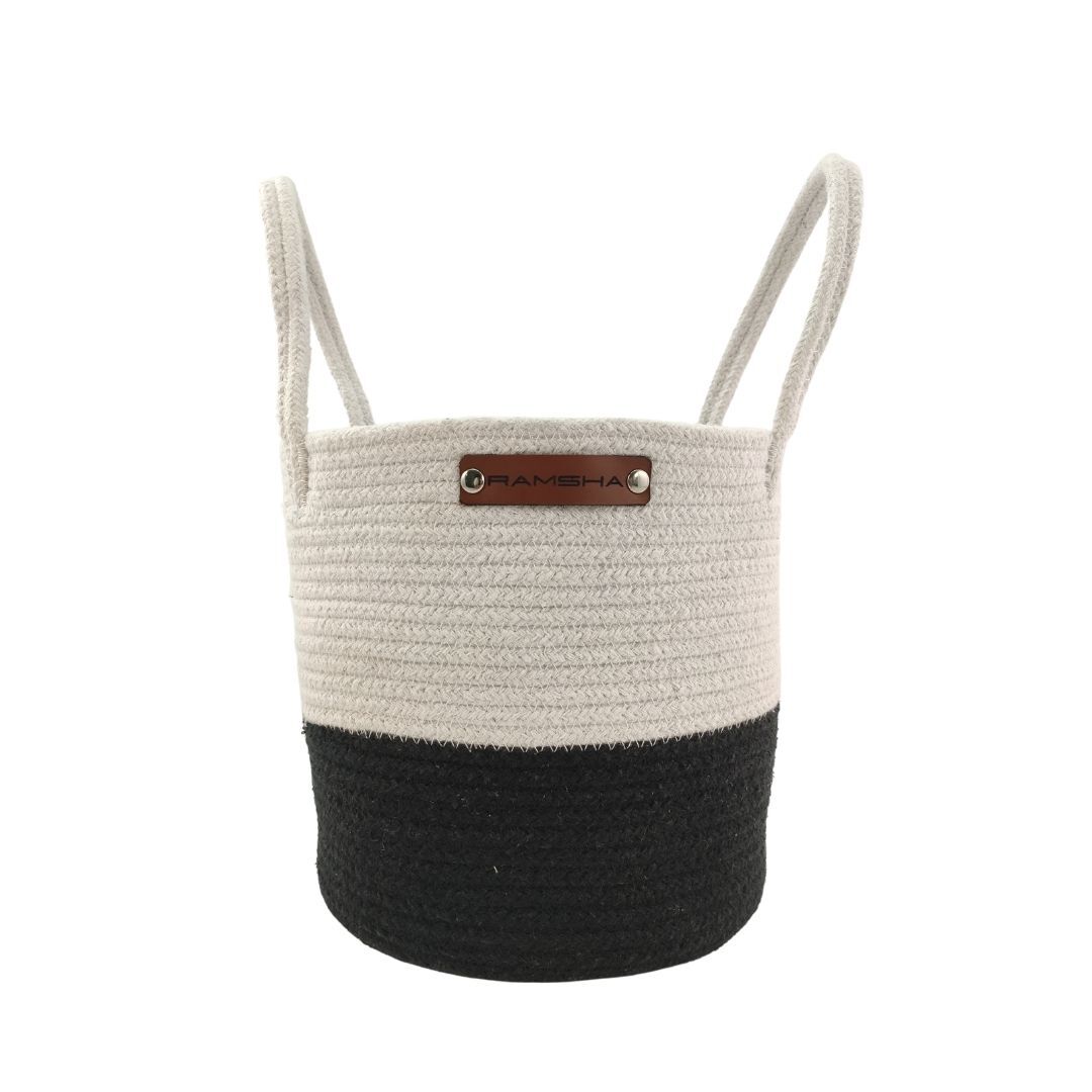 The Ramsha Home Cotton White & Black Handmade Basket - BS 006 (25x25cm) features handles, a white upper half, black lower half, and a front label. Ideal for nurseries or decor, this luxury storage basket adds style to your home.