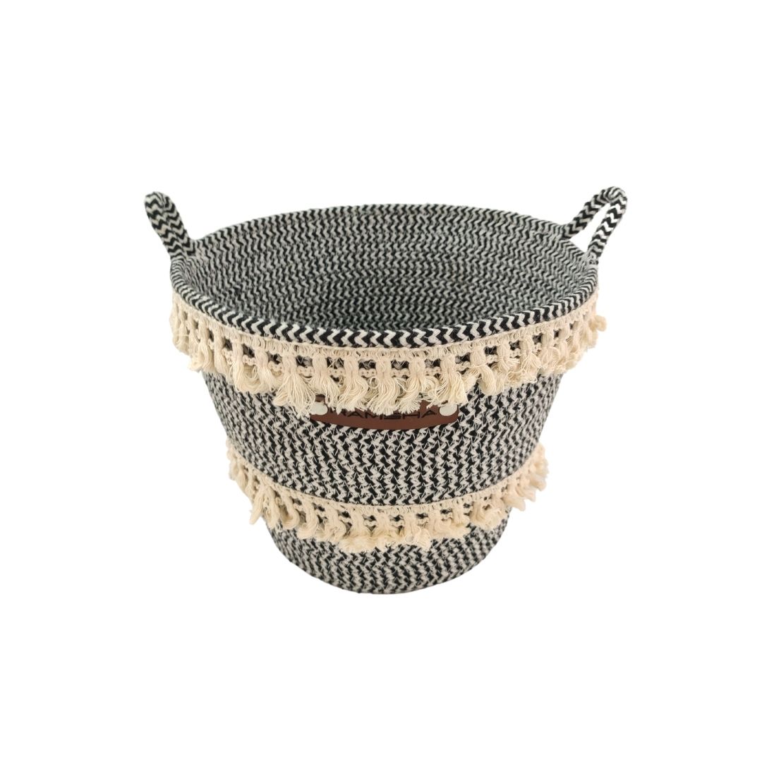 Two Ramsha Home White and Black Handmade Cotton Baskets with handles (BS 009, 25x20x25cm), each adorned with cream fringe tassels, stacked for stylish nursery storage. Luxury UAE home furnishing.
