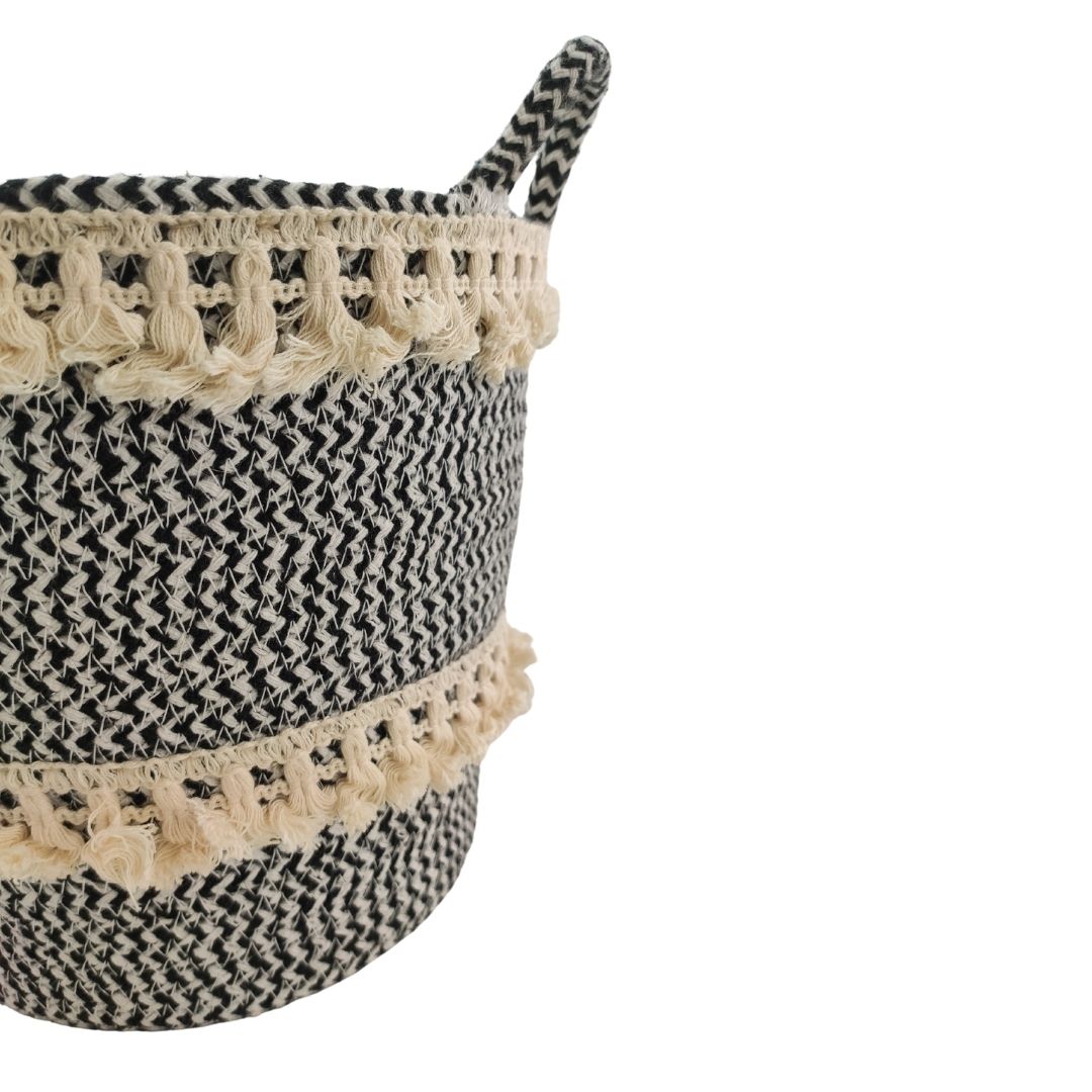 The Ramsha Home White and Black Handmade Cotton Basket with Handle (BS 009, 25x20x25cm) features decorative fringe accents, perfect for adding style to nursery organization.