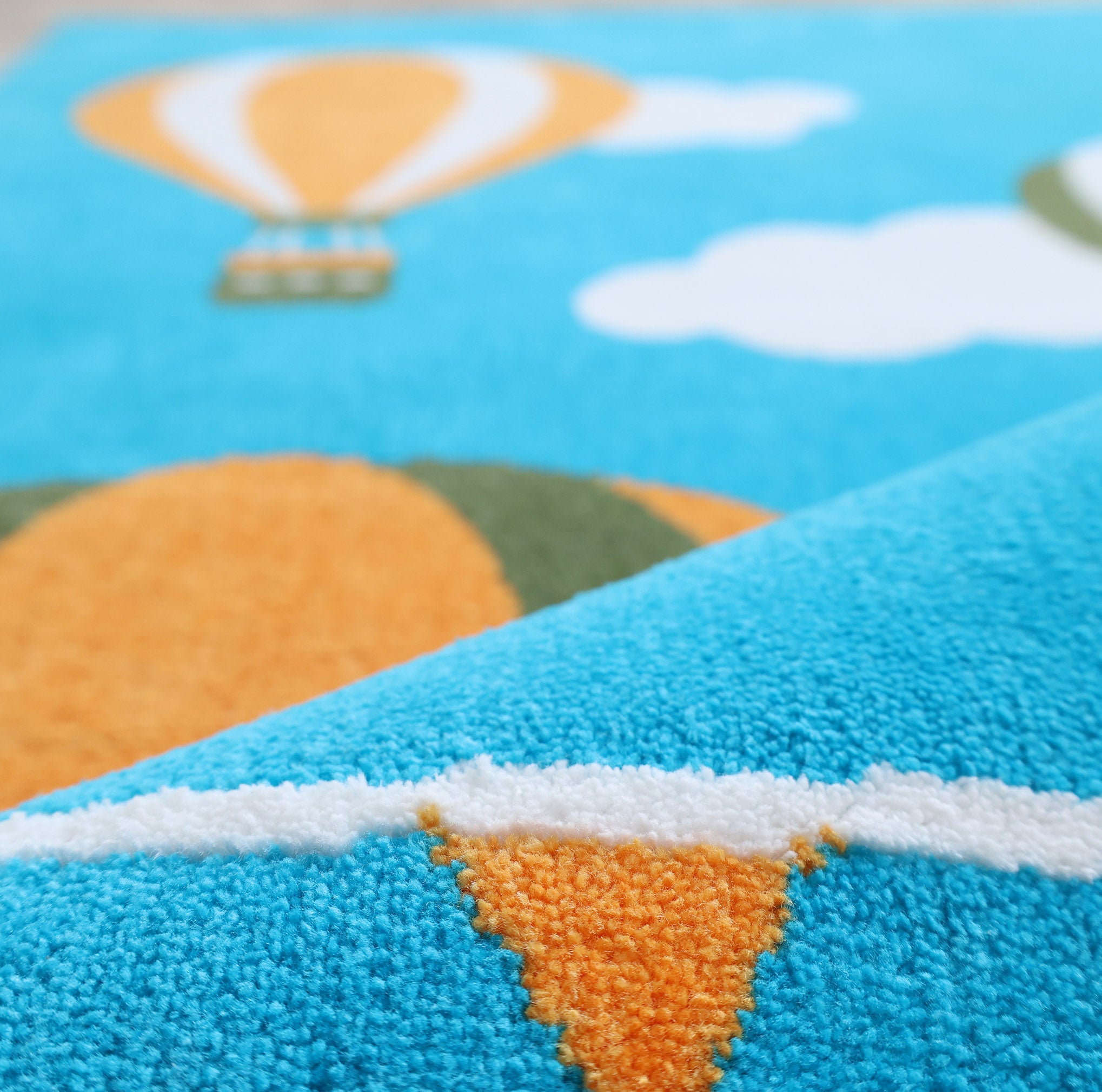 Close-up of the RAMSHA HOME Kids Play Rug with Clouds & Balloons (CMN 101, 200x300 cm) shows an orange and white balloon with clouds on a bright blue background—its detailed texture makes it ideal for any playful kids’ room.