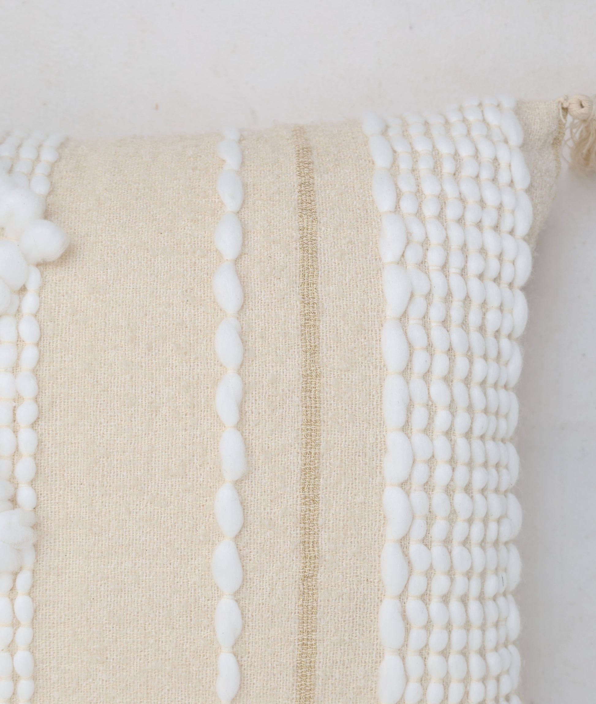 Close-up of the Cream Color Home Decor Cushion - CS 313 A by Ramsha Home, featuring premium cotton, vertical white pompom accents, and a tan stripe—an elegant touch to your décor.