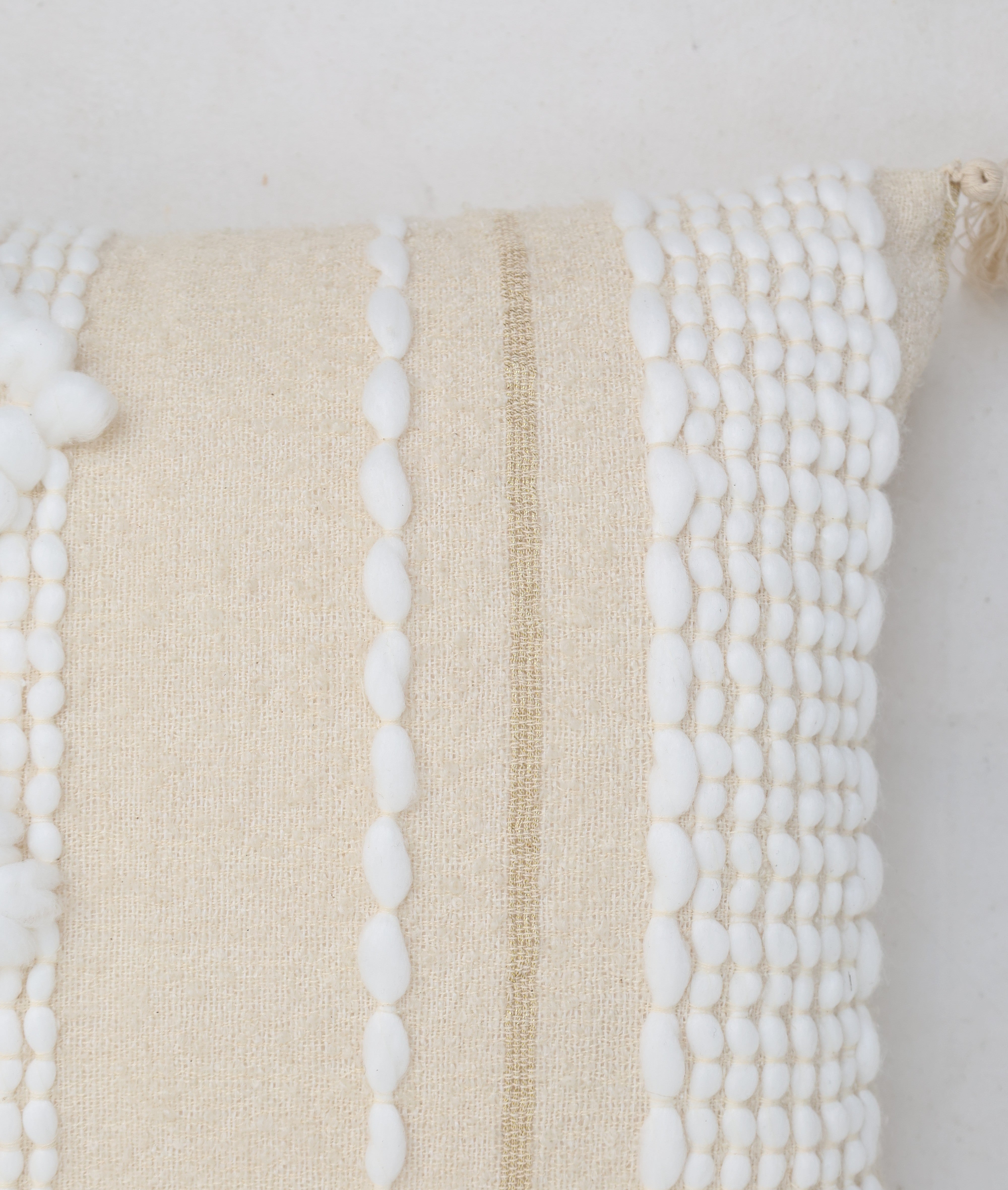 Close-up of the Cream Color Home Decor Cushion - CS 313 A by Ramsha Home, featuring premium cotton, vertical white pompom accents, and a tan stripe—an elegant touch to your décor.
