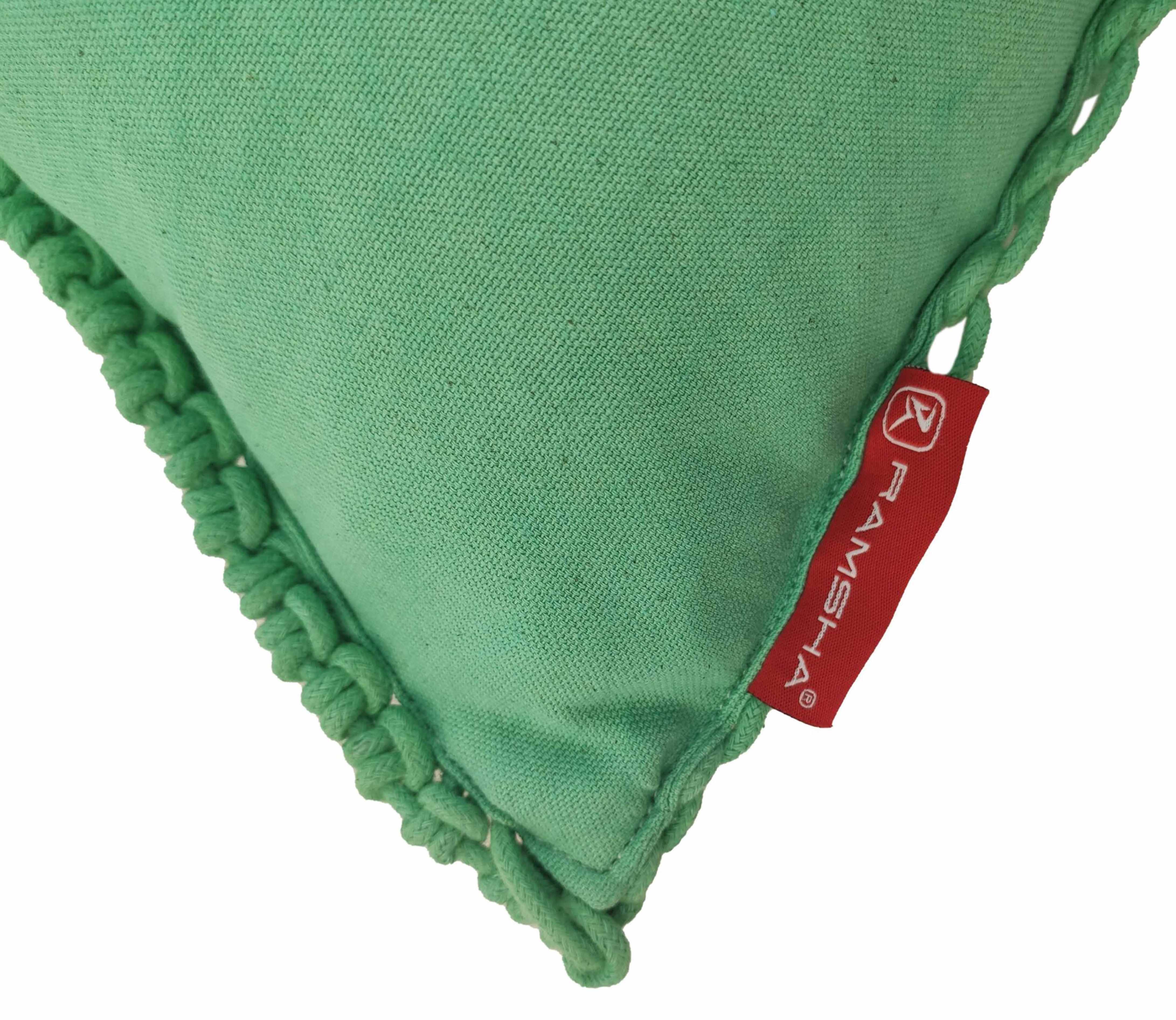 Close-up of the Macrame Cotton Cushion With Filler by RAMSHA HOME, featuring green cotton with braided edges and a red brand tag—ideal as a decorative cushion.