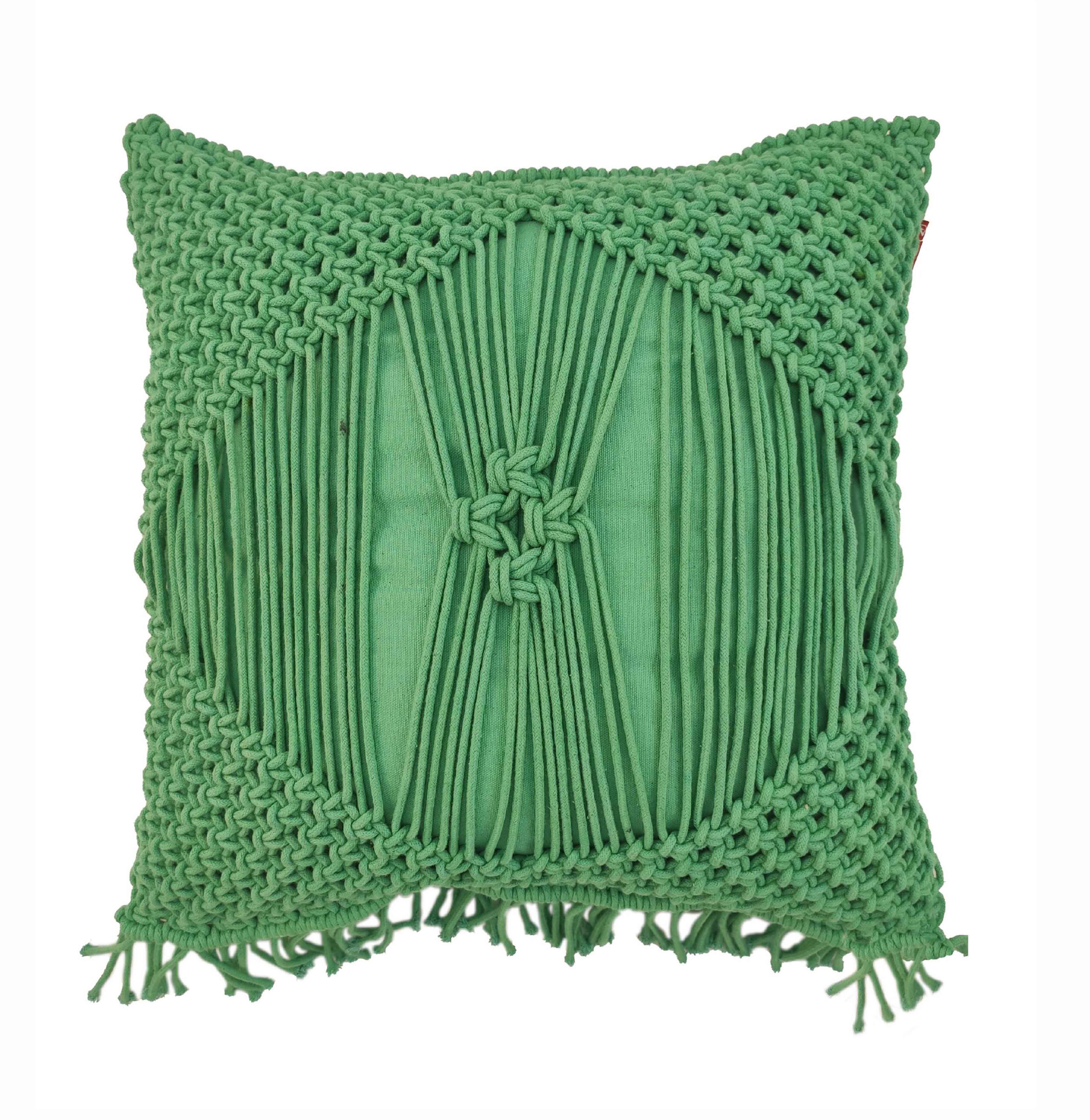 The RAMSHA HOME Macrame Cotton Cushion With Filler is a green, square cushion with a textured woven design, knotted patterns, and fringed corners. Its center features vertical strands forming a star-like knot for decorative appeal.