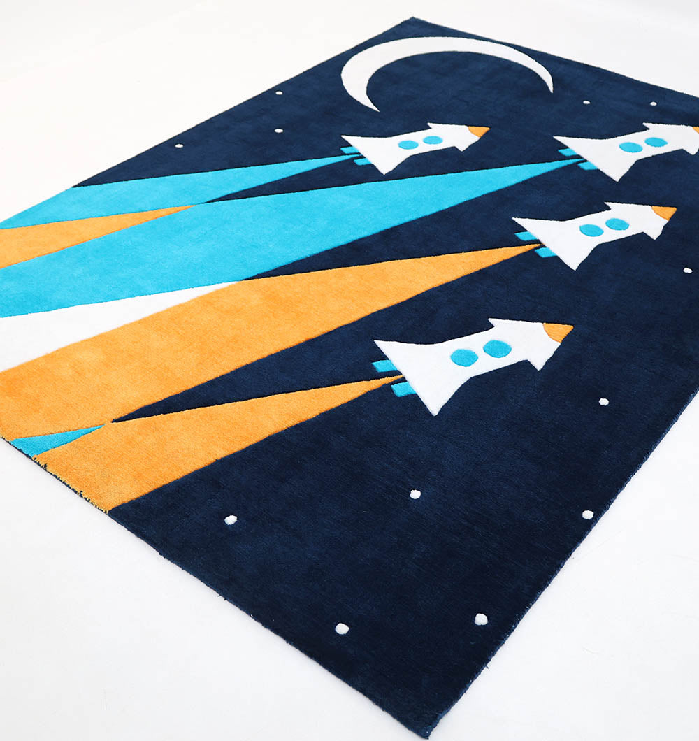 The RAMSHA HOME Kids Space Rocket Polyester Playroom Rug KD-001 (170x240cm) has four white rockets, blue windows, orange/blue exhausts, a crescent moon, and stars on a dark blue background—perfect for adventurous bedrooms.