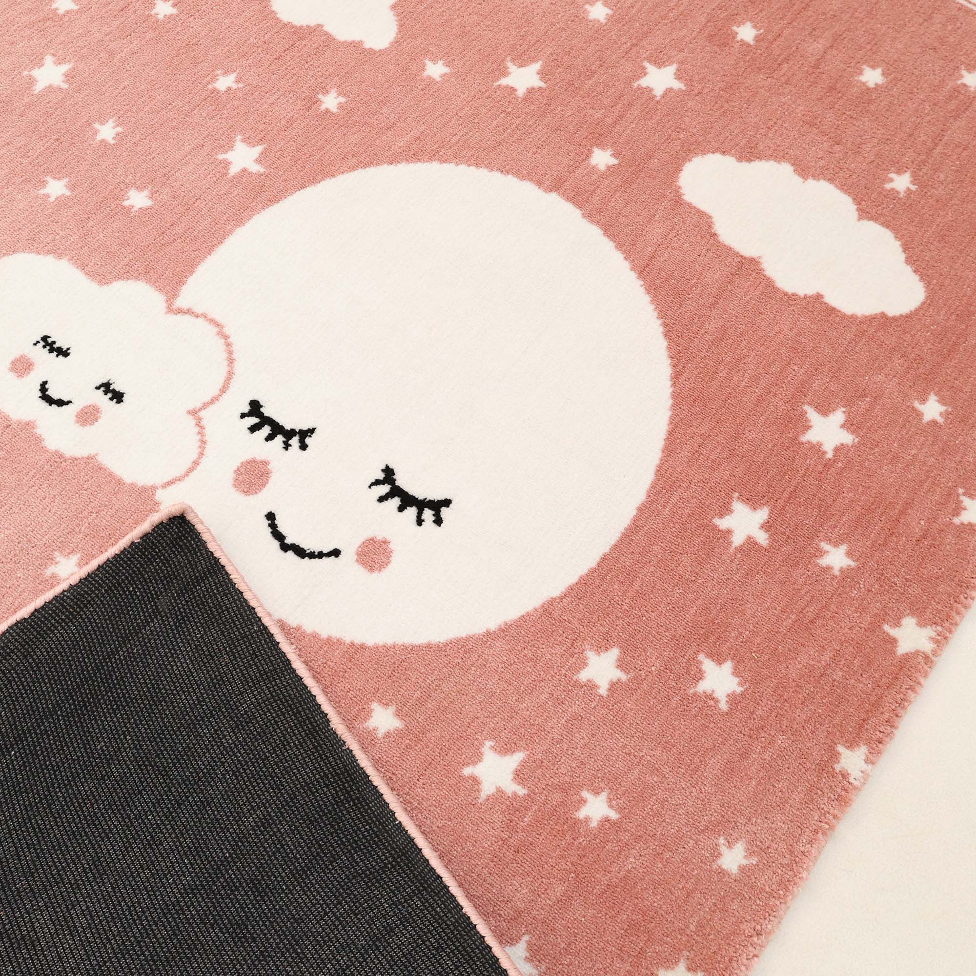 The RAMSHA HOME Kids Rug Soft Star & Sky Pink Color Nursery Rug (120x180 cm – KD 019) features white stars, clouds, and a smiling moon with rosy cheeks—a playful touch perfect for any child’s room or nursery.