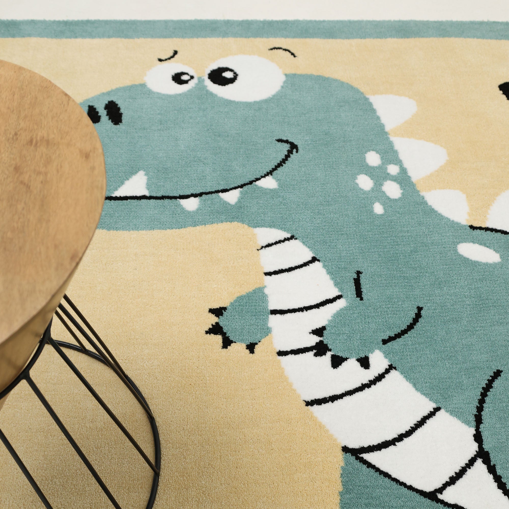 The RAMSHA HOME Kids Rug Soft Dinosaur Character Rug (120x180 cm – KD 018) features a playful green cartoon dinosaur with a white belly and spikes, perfect for adding fun to any kids' room.