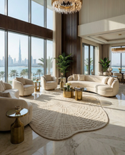 Luxurious living room with cream sofas, RAMSHA HOME’s Home Decor Handmade Area Rug - HTW 112 (200X300 cm), gold tables, large windows with Burj Khalifa views, marble floors, indoor plants, chandeliers, and plenty of natural light.