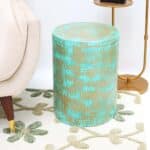 Round modern side table with turquoise dot pattern and golden iron base placed beside a couch