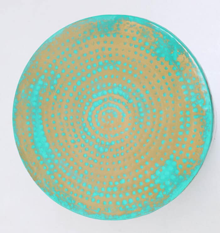 Top view of round coffee table showing turquoise dot pattern on golden iron base