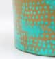 Close-up of round coffee table showing turquoise dot pattern and golden iron base details