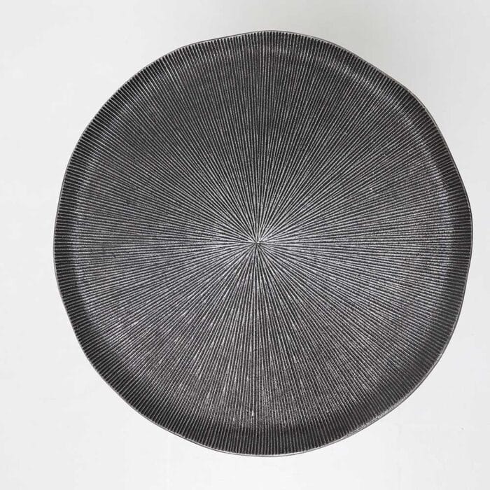 Top view of modern black metal side table showing textured round surface and matte finish