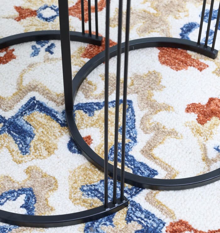 Close-up of black iron base of wooden nesting side tables showing sleek metal frame and sturdy design