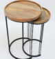 Side angle view of set of 2 wooden nesting side tables showing round solid wood tops and black iron bases