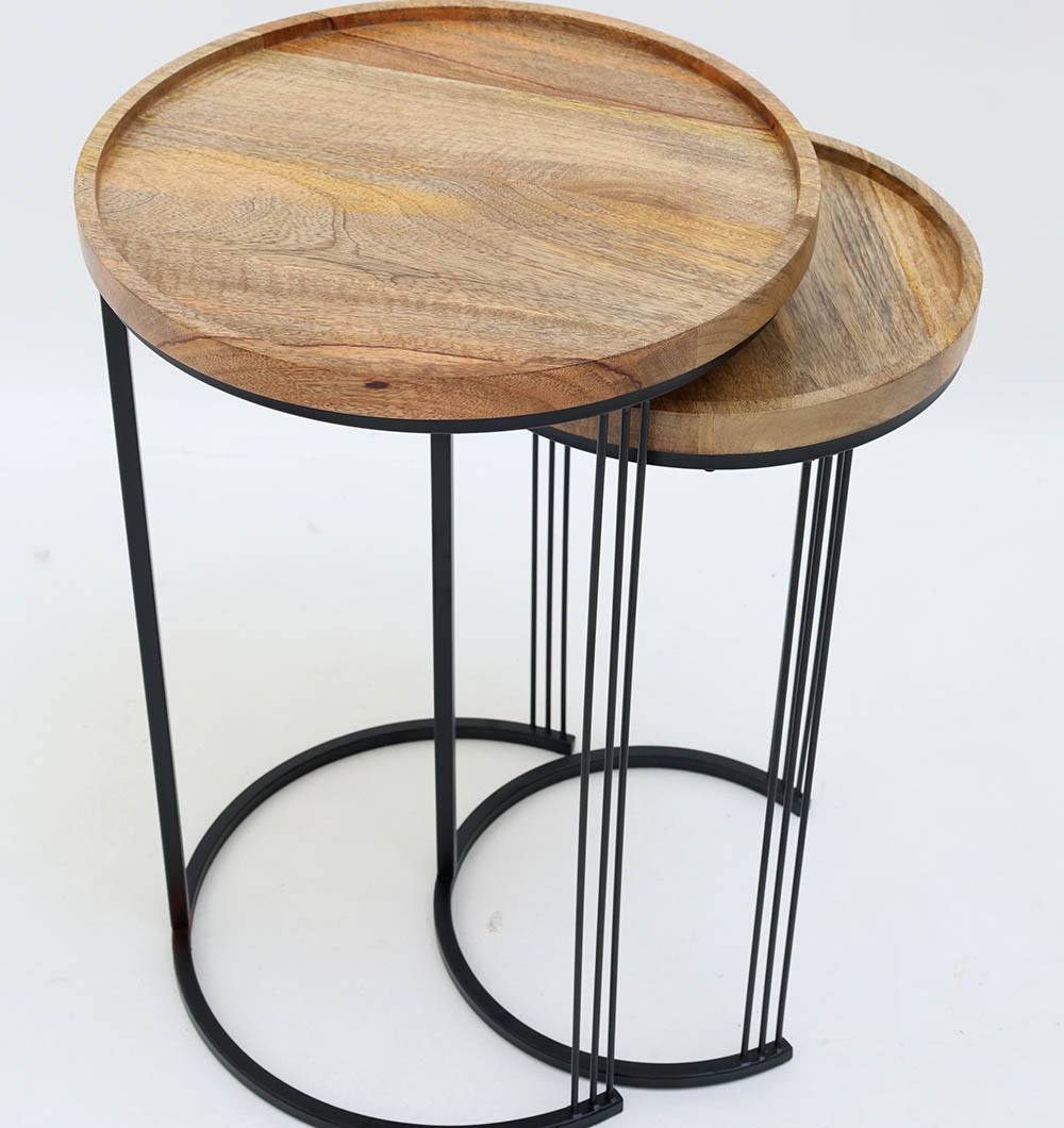 Side Angle – Wooden Nesting Side Tables with Round Solid Wood Tops and Black Iron Bases Side angle view of set of 2 wooden nesting side tables showing round solid wood tops and black iron bases