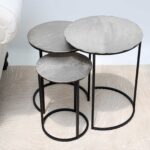 Top angled view of modern round coffee table showing aluminium top texture and black iron legs