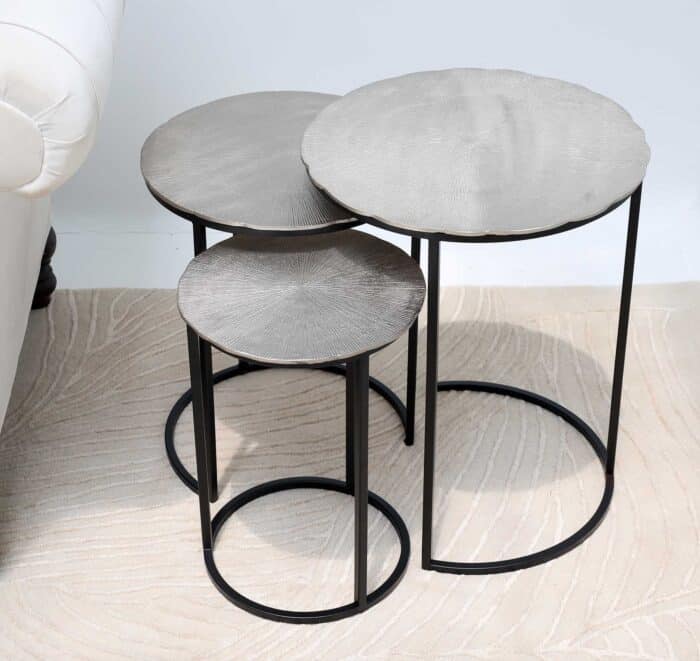 Top angled view of modern round coffee table showing aluminium top texture and black iron legs