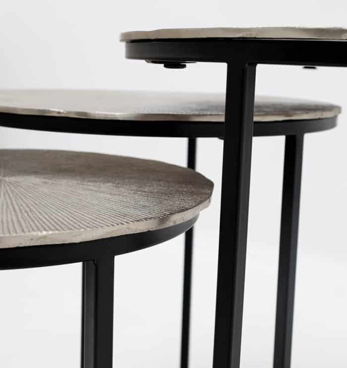 Side close-up of modern round coffee table showing aluminium top texture and black iron legs