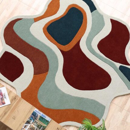 A Curvy Abstract Round Rug with fluid, wavy color blocks in terracotta, orange, and teal with a unique irregular silhouette.