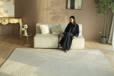 A spacious modern living room featuring a large grey rectangular rugs anchoring a sectional sofa and coffee table.